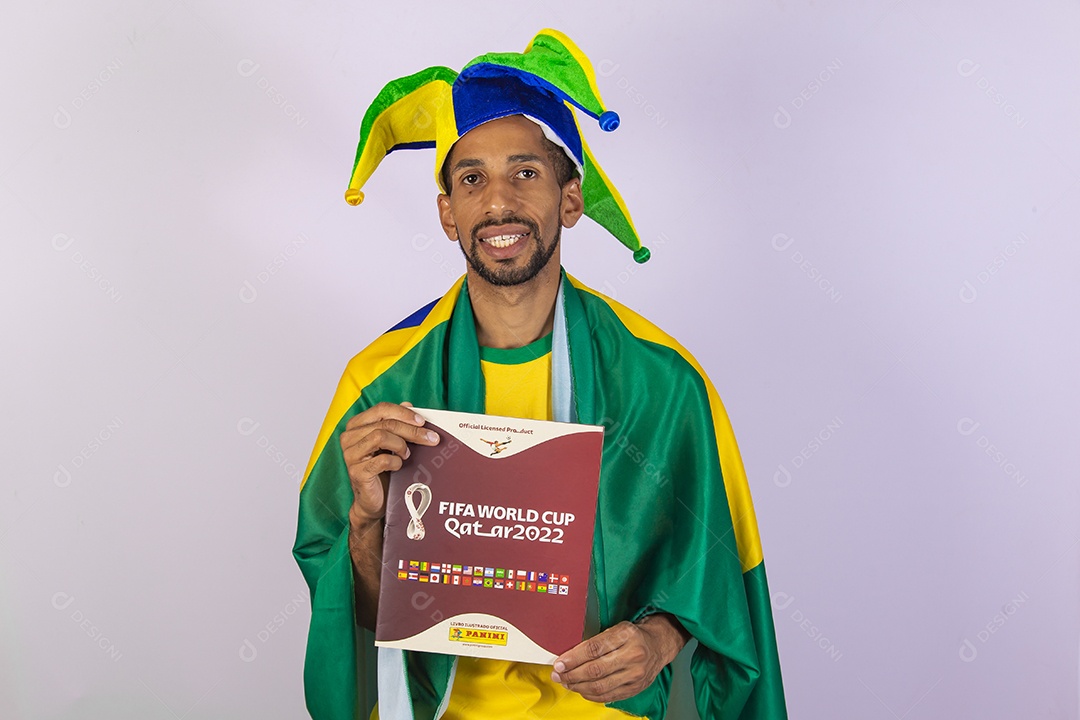 Homem brasileiro vestindo uma camiseta do Brasil e segurando um álbum da copa