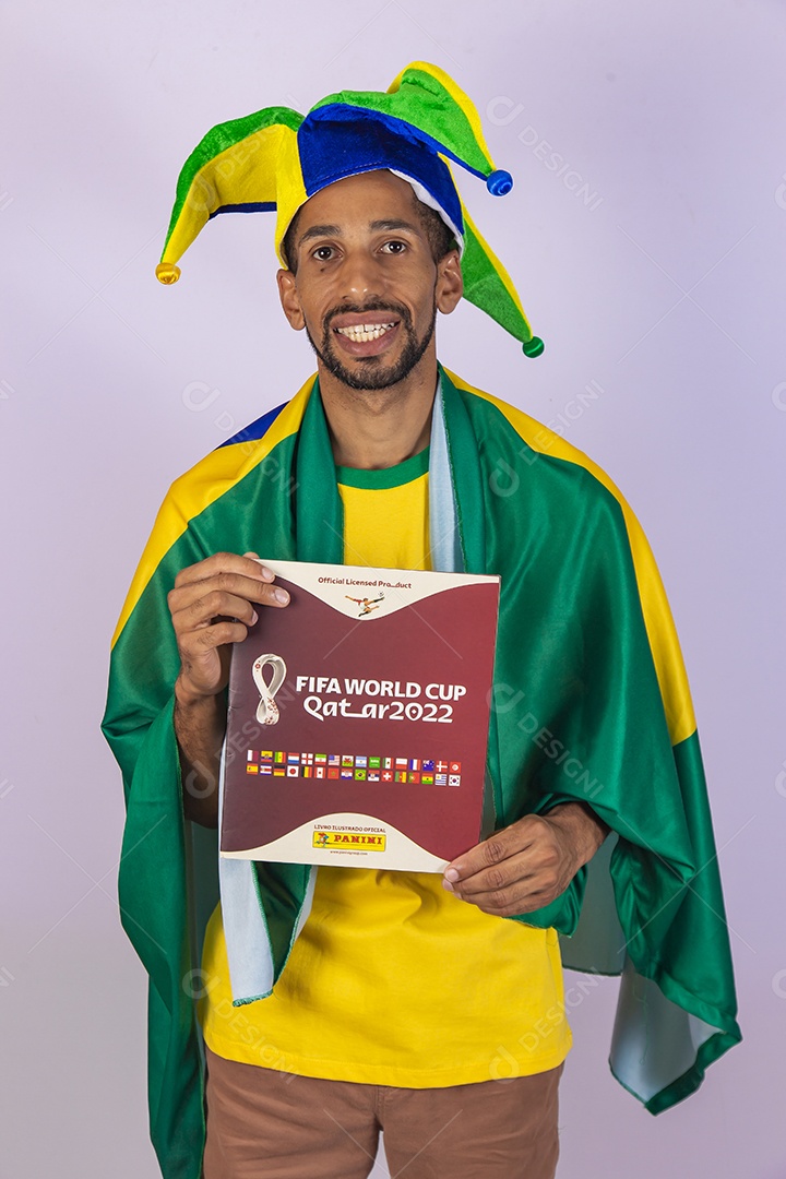 Homem brasileiro usando uma camiseta do Brasil e segurando um álbum da copa do mundo