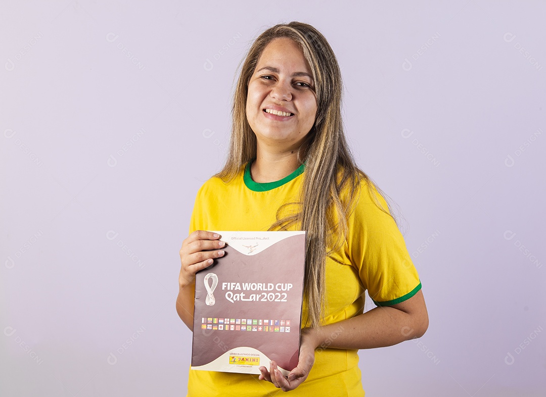 Linda mulher jovem morena segurando álbum da copa do brasil de 2022 futebol
