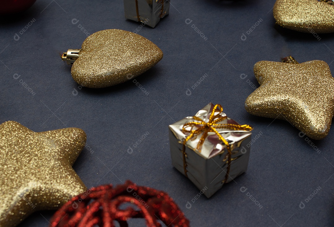 vários enfeites de natal dourados e vermelho em fundo preto