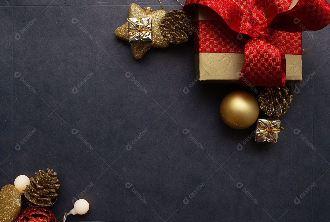 caixa de presente com vários enfeites de natal dourados e vermelho ao redor em fundo preto