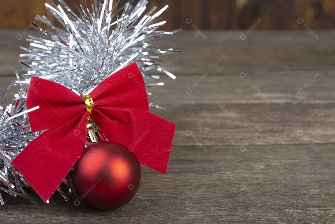 Bolas vermelhas de natal e laço de presente sobre a mesa de madeira.