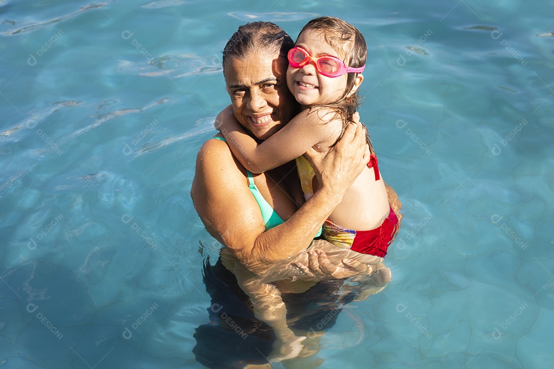 Família banhando e brincando na piscina de água azul.
