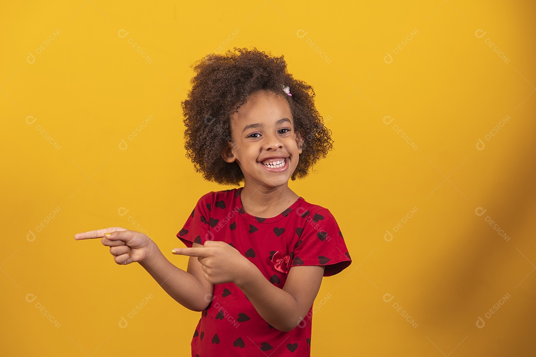 Linda menina criança apontando para lado sobre fundo isolado amarelo