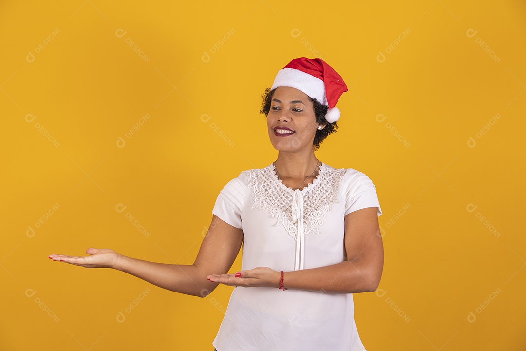 Linda mulher jovem apontando para lado usando gorro do Papai Noel