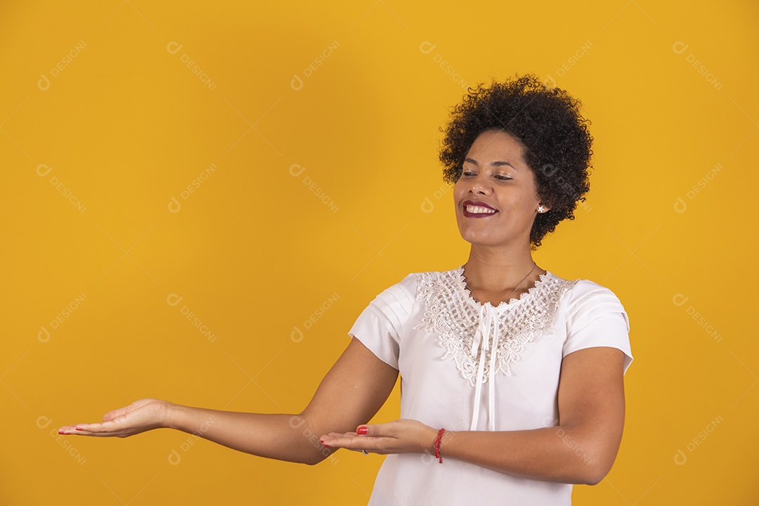 Linda mulher jovem apontando para lado cabelo afro sobre fundo isolado amarelo