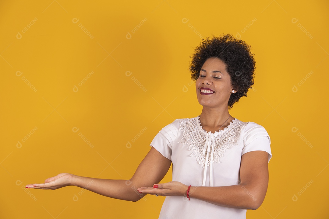 Linda mulher jovem cabelo afro apontando para lado sobre fundo isolado amarelo
