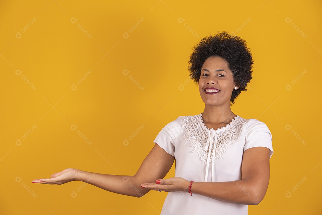 Linda mulher jovem apontando para lado cabelo afro sobre fundo isolado amarelo