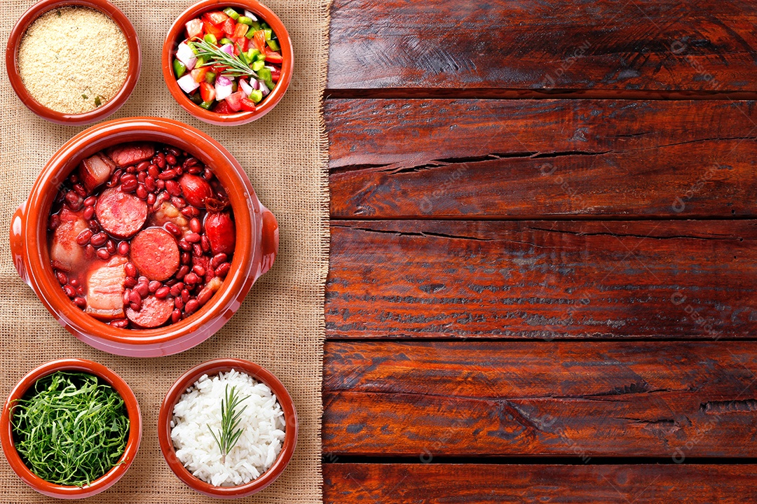 Feijoada brasileira, comida tradicional da culinária do Brasil, na caçarola de cerâmica, sobre mesa de madeira rústica. vista do topo