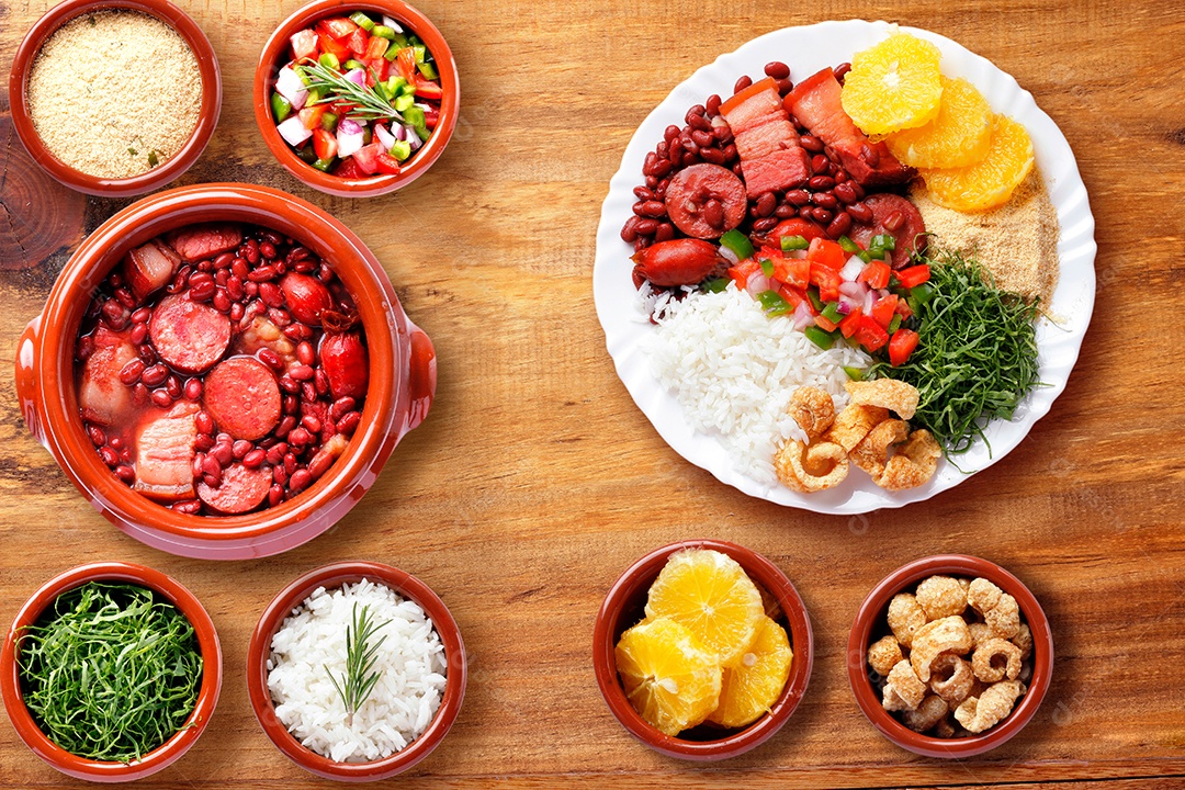 Feijoada brasileira, comida tradicional da cozinha brasileira, na chapa branca, sobre mesa de madeira rústica. vista do topo