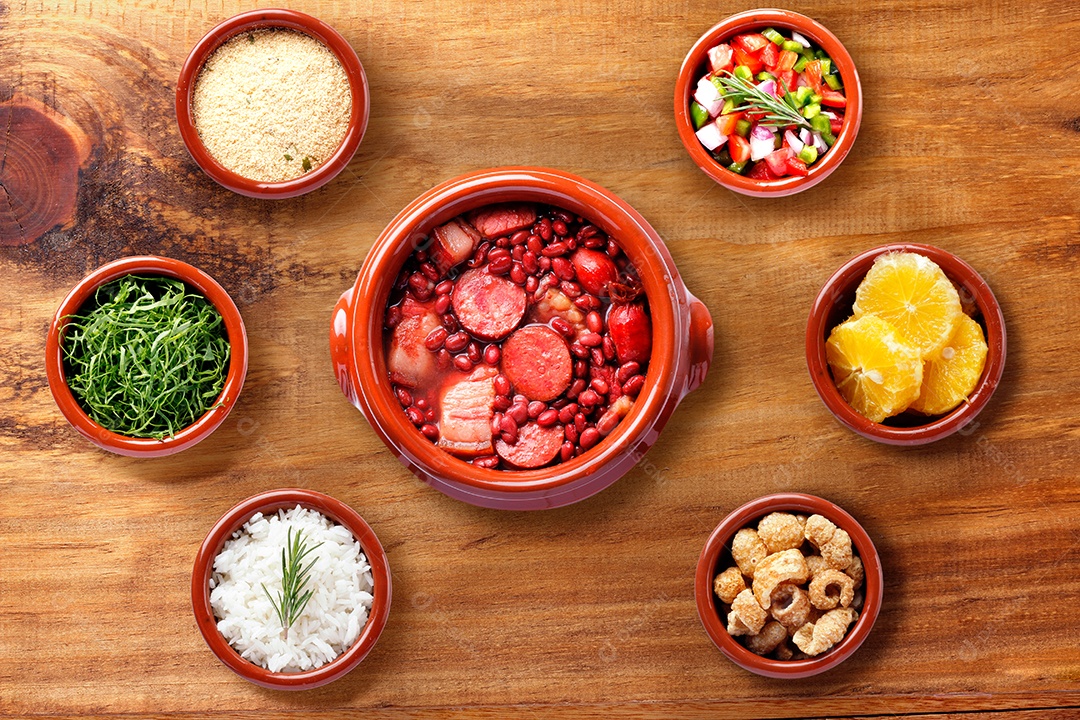 Feijoada brasileira, comida tradicional da culinária do Brasil, na caçarola de cerâmica, sobre mesa de madeira rústica. vista do topo