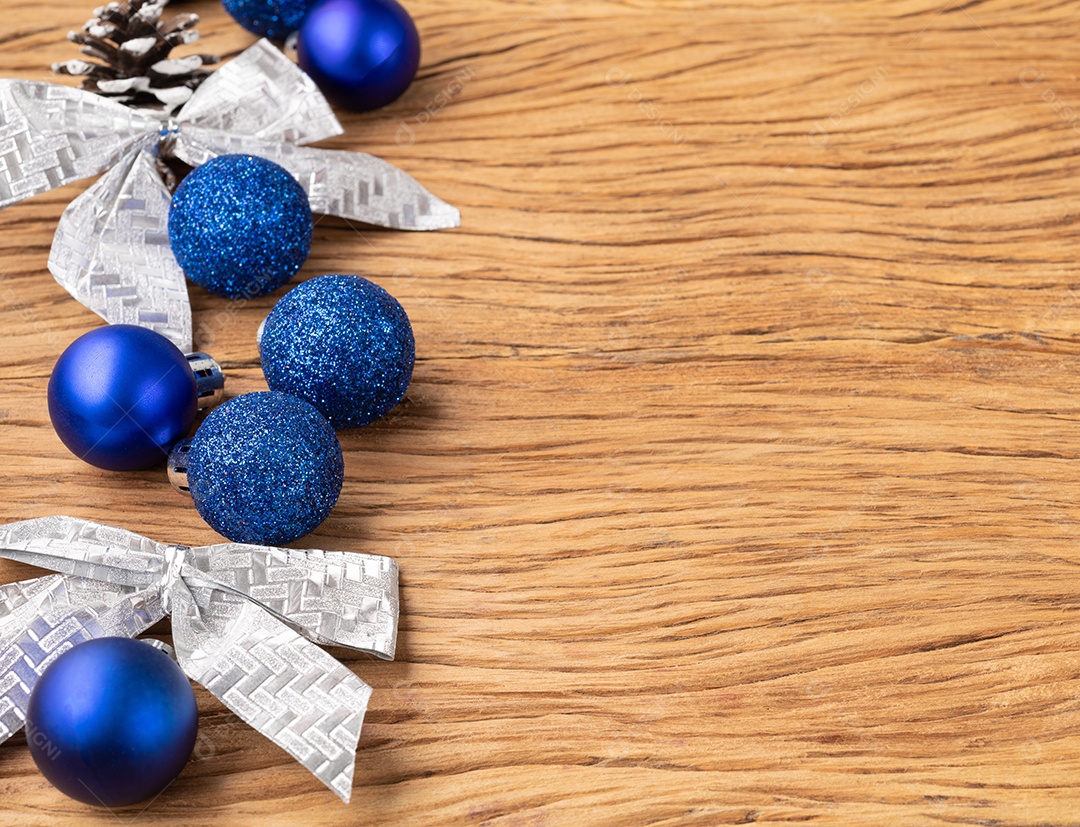 Bolas de natal, pinha e arco sobre mesa de madeira.