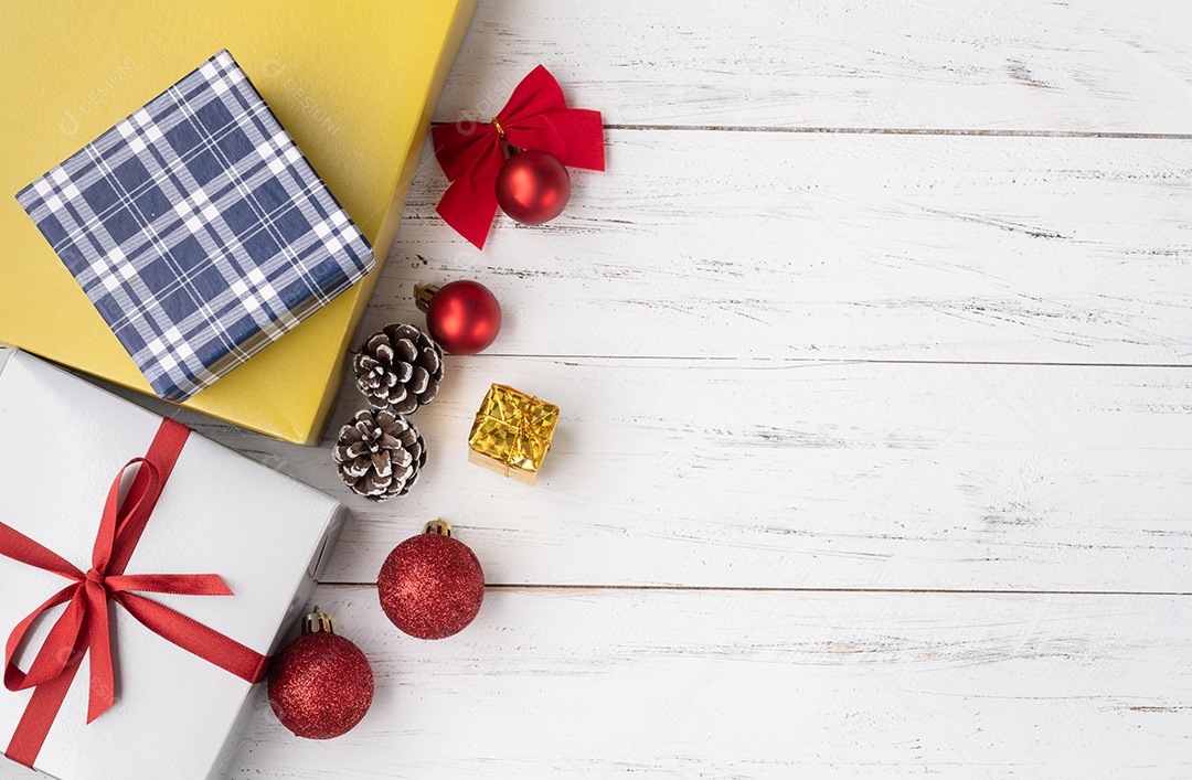 Caixa de presente, bolas de natal e arco sobre mesa de madeira com espaço de cópia.
