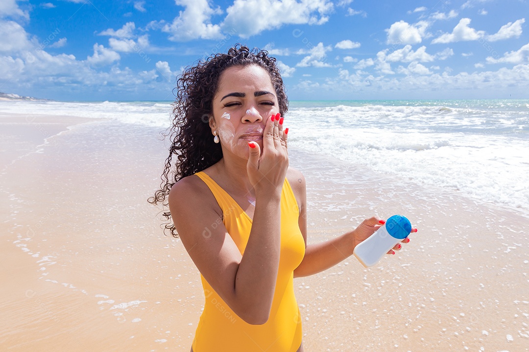 Linda mulher sobre uma praia usando protetor solar