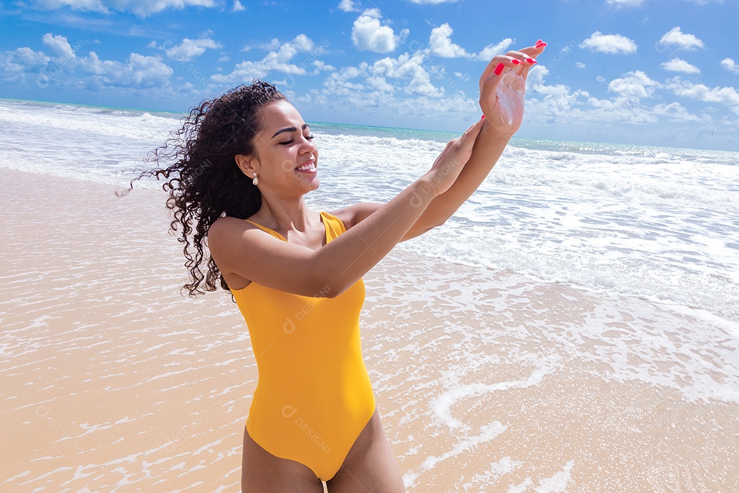Linda mulher sobre uma praia usando protetor solar