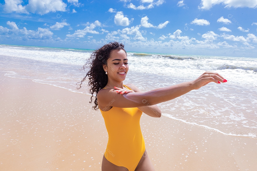 Linda mulher sobre uma praia usando protetor solar