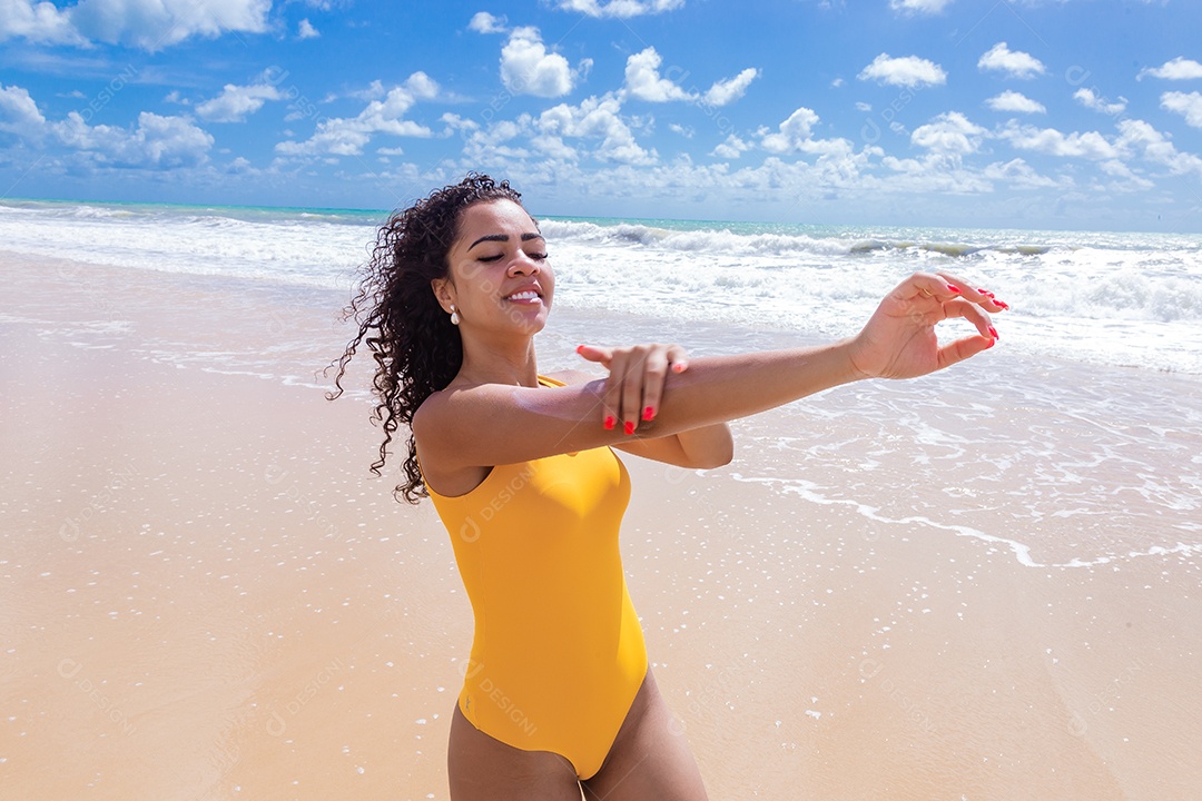 Linda mulher sobre uma praia usando protetor solar