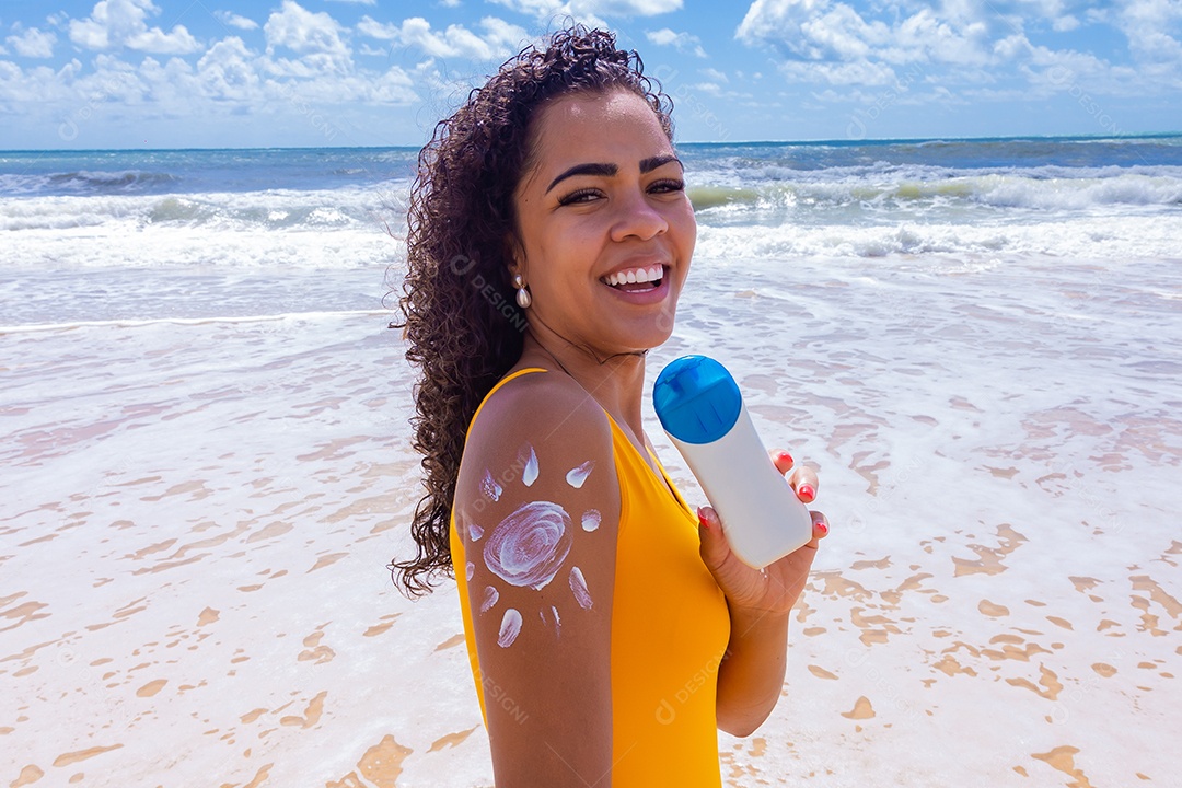 Linda mulher sobre uma praia usando protetor solar