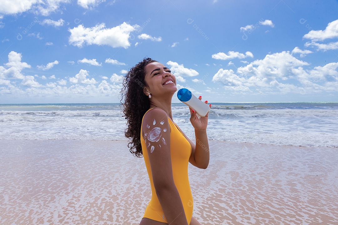 Linda mulher sobre uma praia usando protetor solar