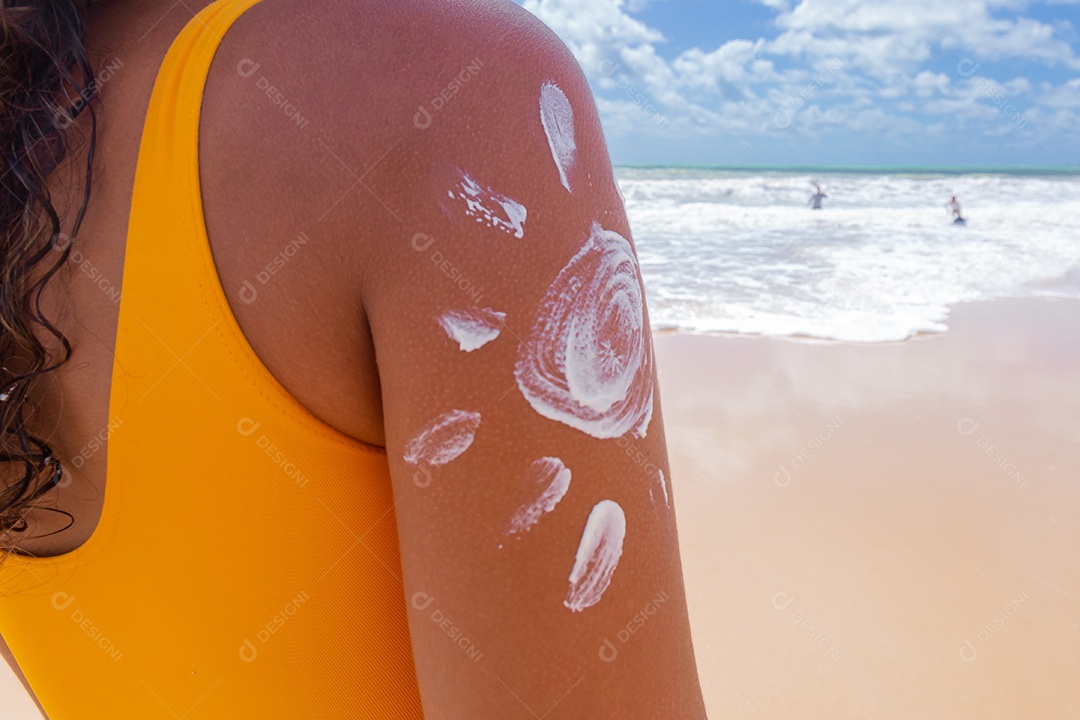 Linda mulher sobre uma praia usando protetor solar
