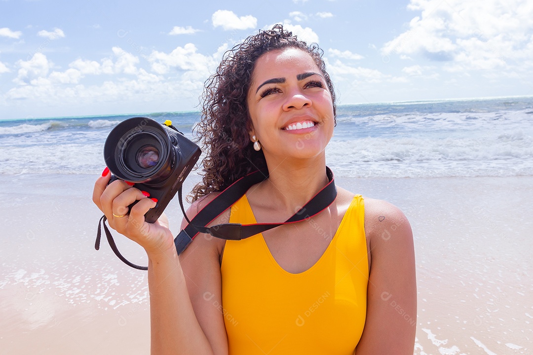 Mulher jovem segurando câmera fotográfica fotografando praia