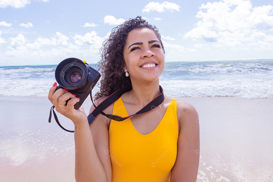Mulher jovem segurando câmera fotográfica fotografando praia