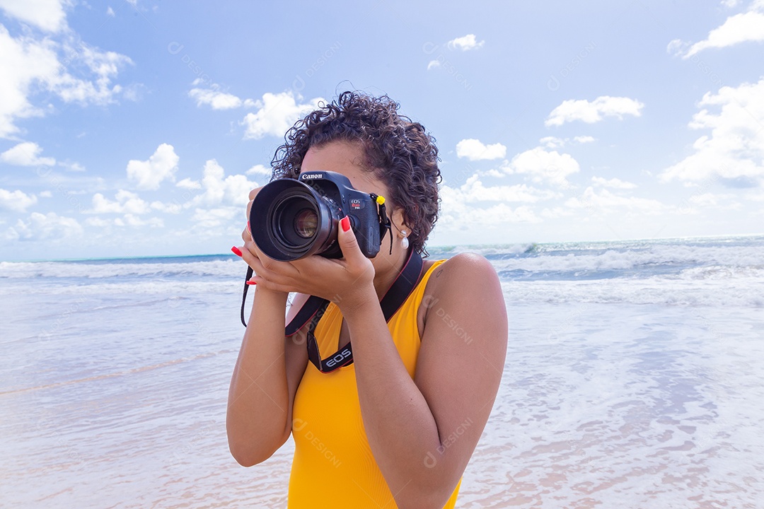 Mulher jovem segurando câmera fotográfica fotografando praia