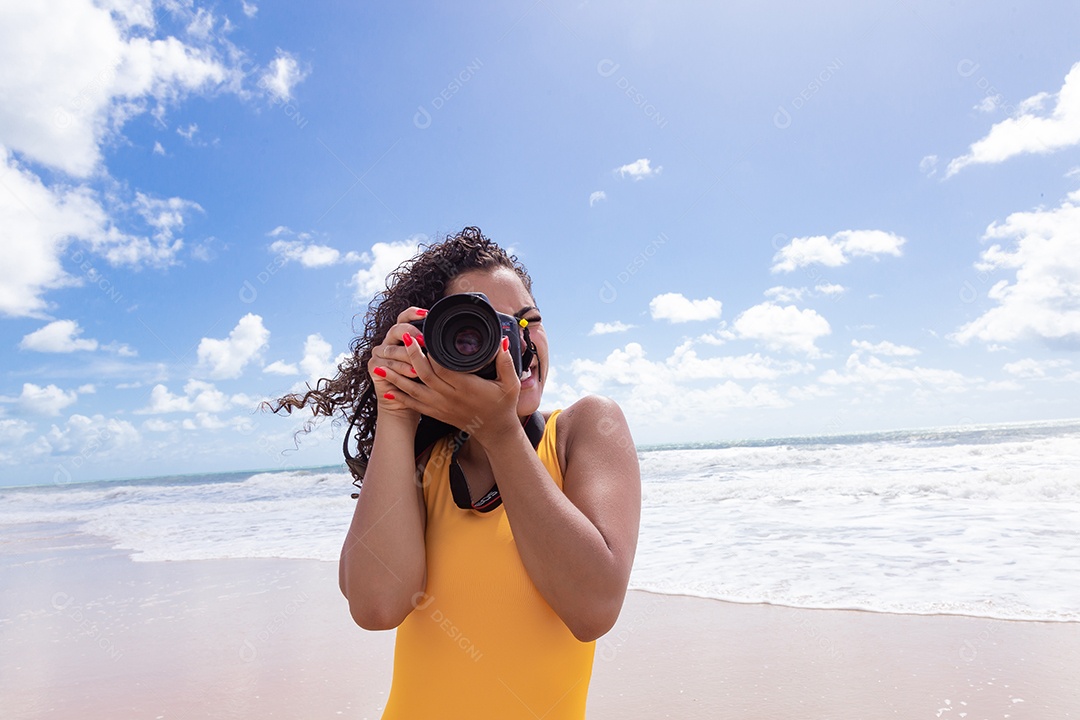 Mulher jovem segurando câmera fotográfica fotografando praia