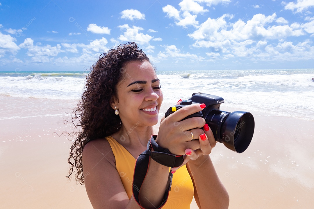 Mulher jovem segurando câmera fotográfica fotografando praia