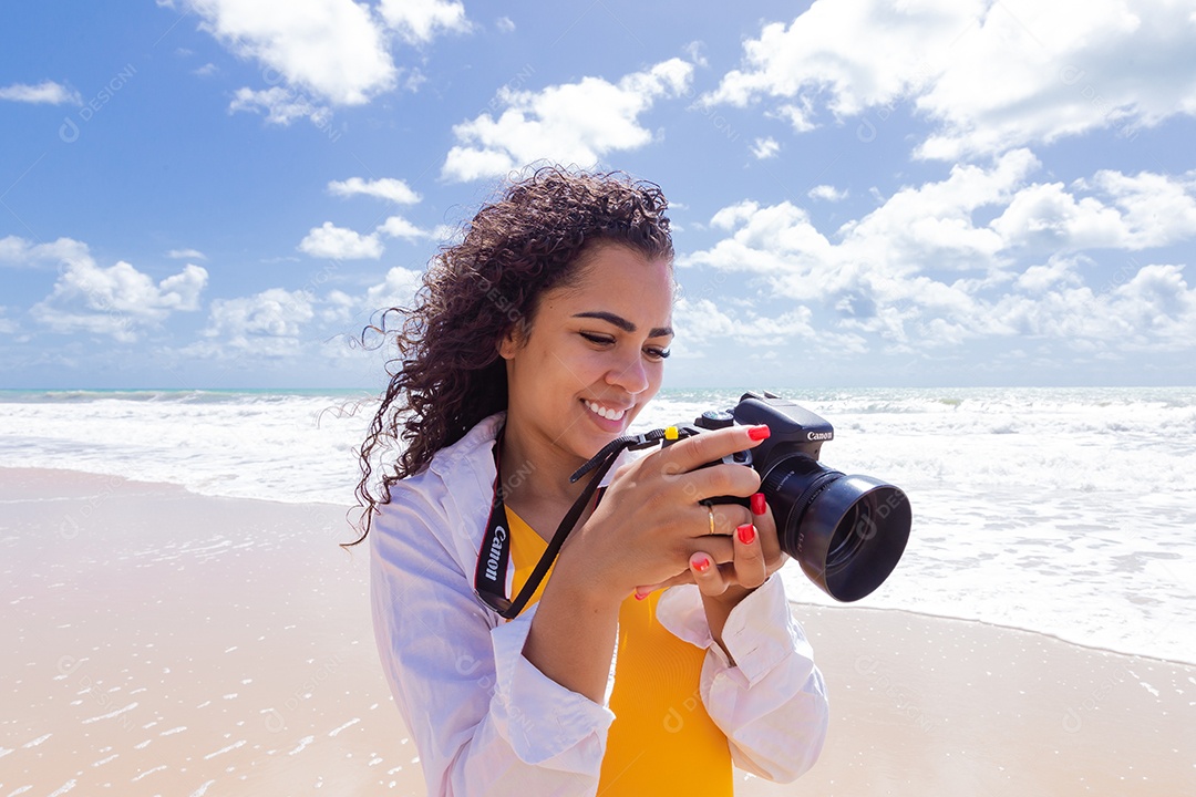 Mulher jovem segurando câmera fotográfica fotografando praia