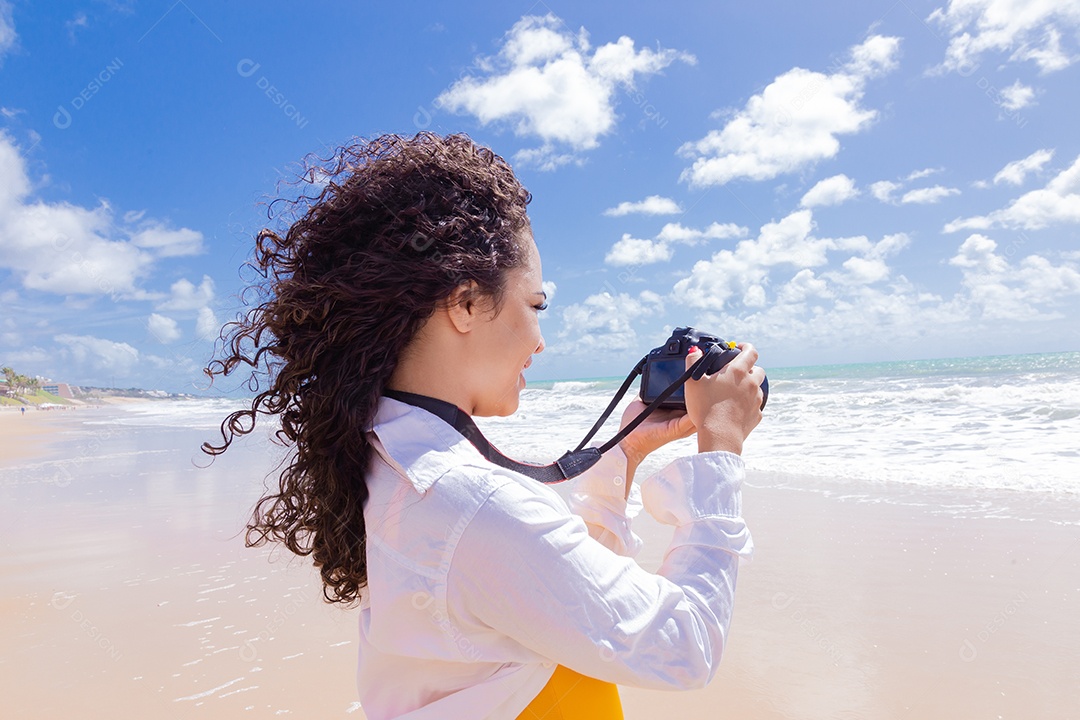 Mulher jovem segurando câmera fotográfica fotografando praia