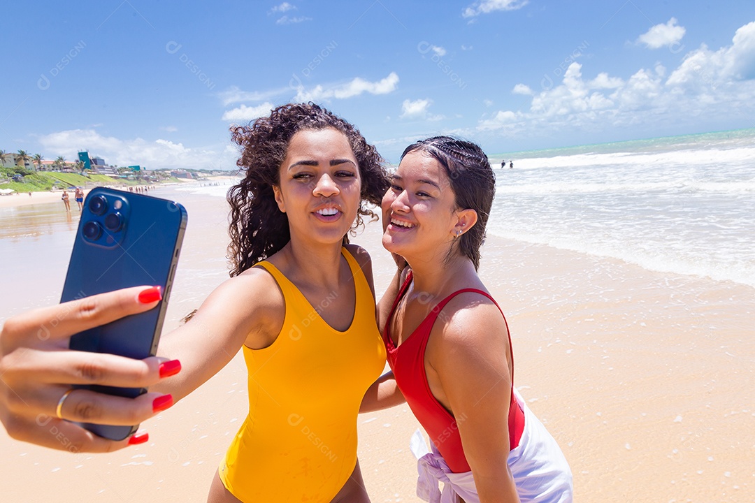 Lindas mulheres usando trajes de banho sobre praia curtindo verão