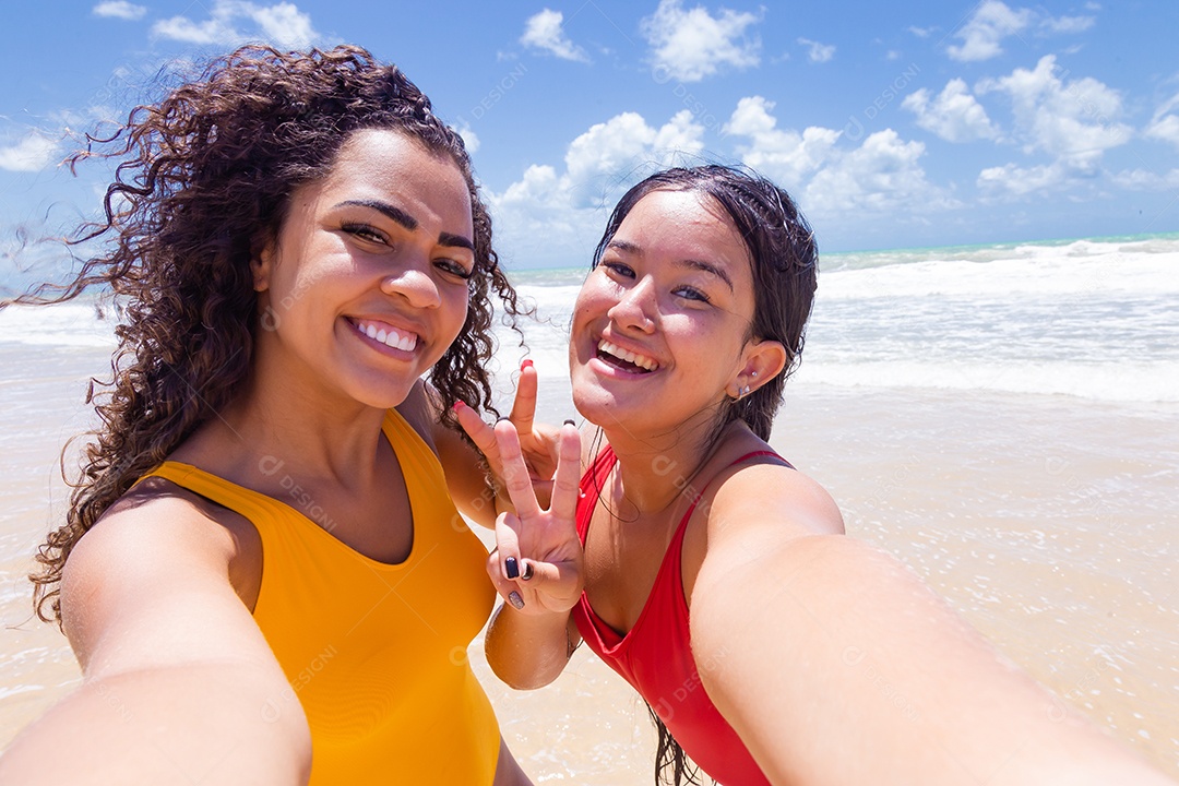 Lindas mulheres tirando selfie usando trajes de banho sobre praia curtindo verão