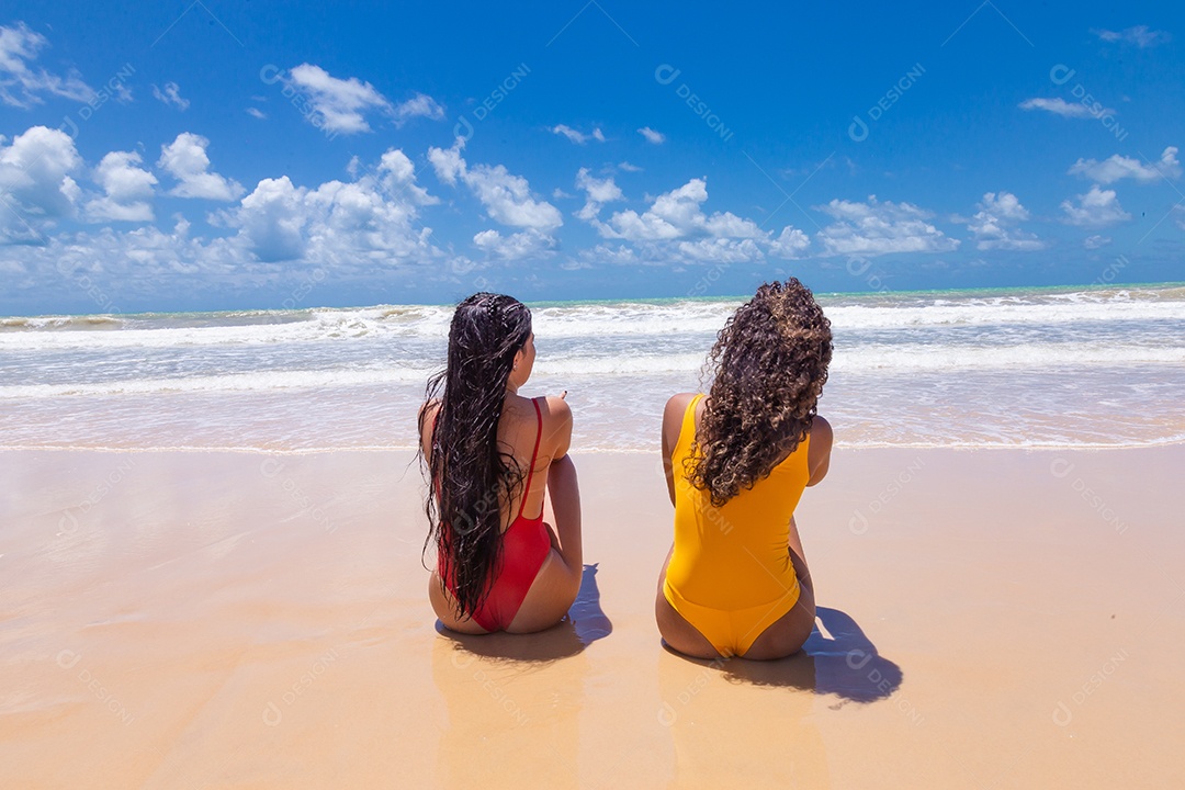 Lindas mulheres usando trajes de banho sobre praia curtindo verão