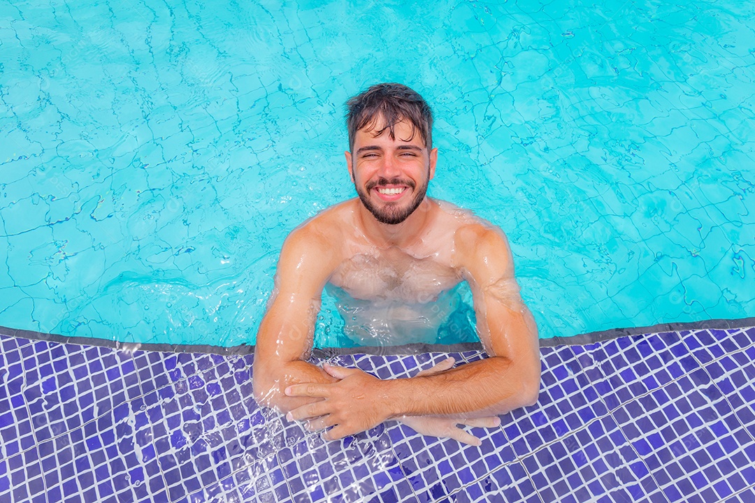 Homem jovem curtindo férias sobre uma piscina