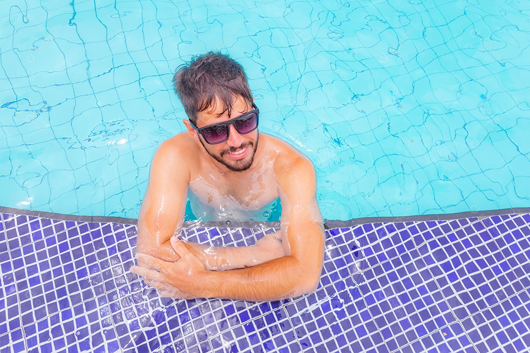 Homem jovem curtindo férias sobre uma piscina