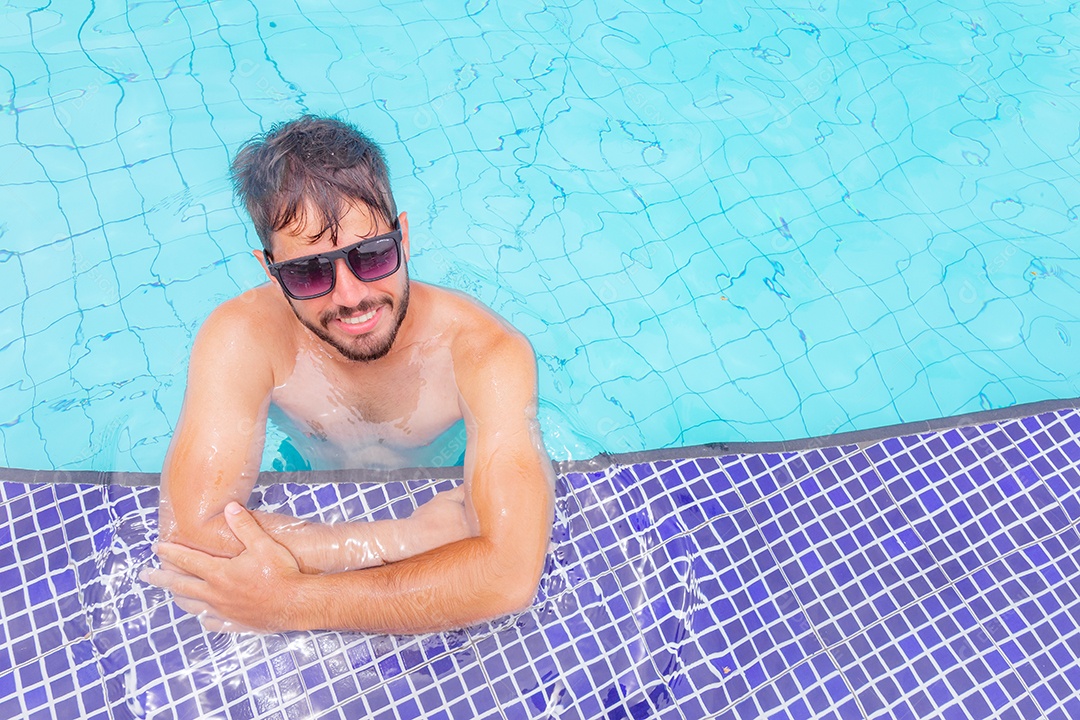 Homem jovem curtindo férias sobre uma piscina