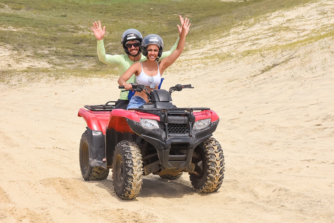 Pessoas curtindo férias andando de quadriciclo sobre dunas