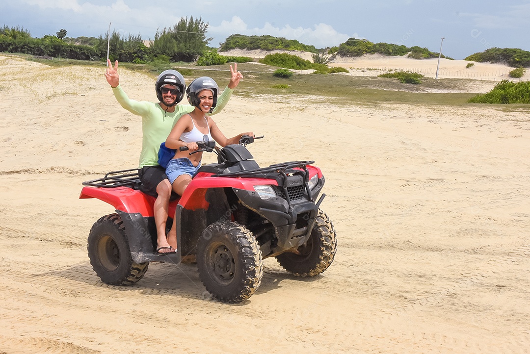 Casal curtindo férias andando de quadriciclo sobre dunas