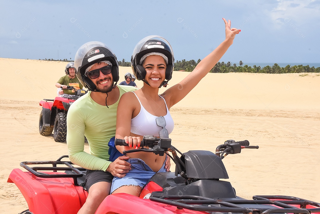 Pessoas curtindo férias andando de quadriciclo sobre dunas