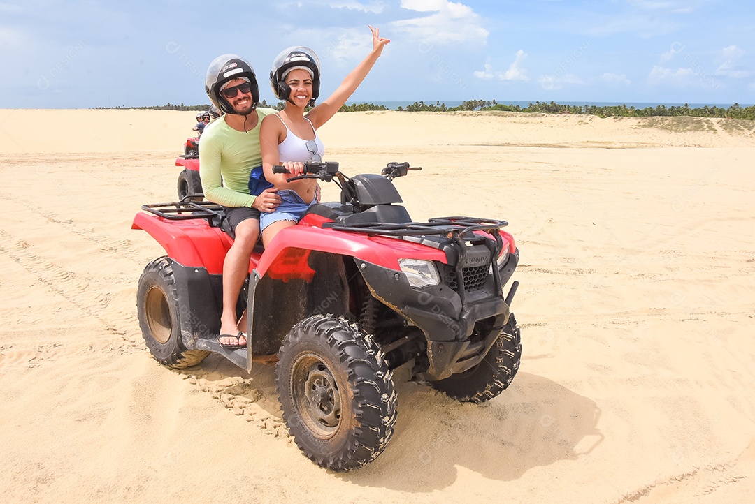 Pessoas curtindo férias andando de quadriciclo sobre dunas