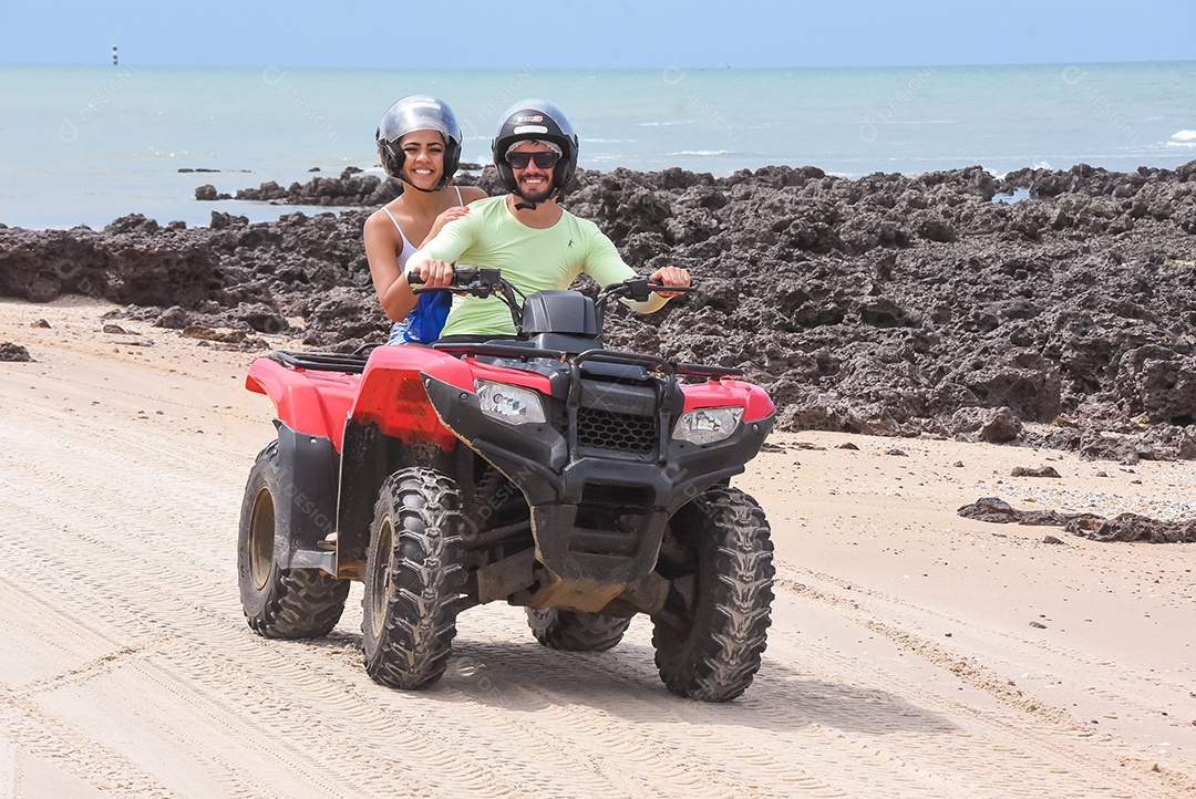 Casal curtindo férias andando de quadriciclo sobre dunas