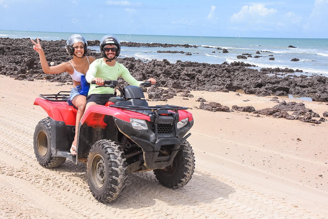 Casal curtindo férias andando de quadriciclo sobre dunas