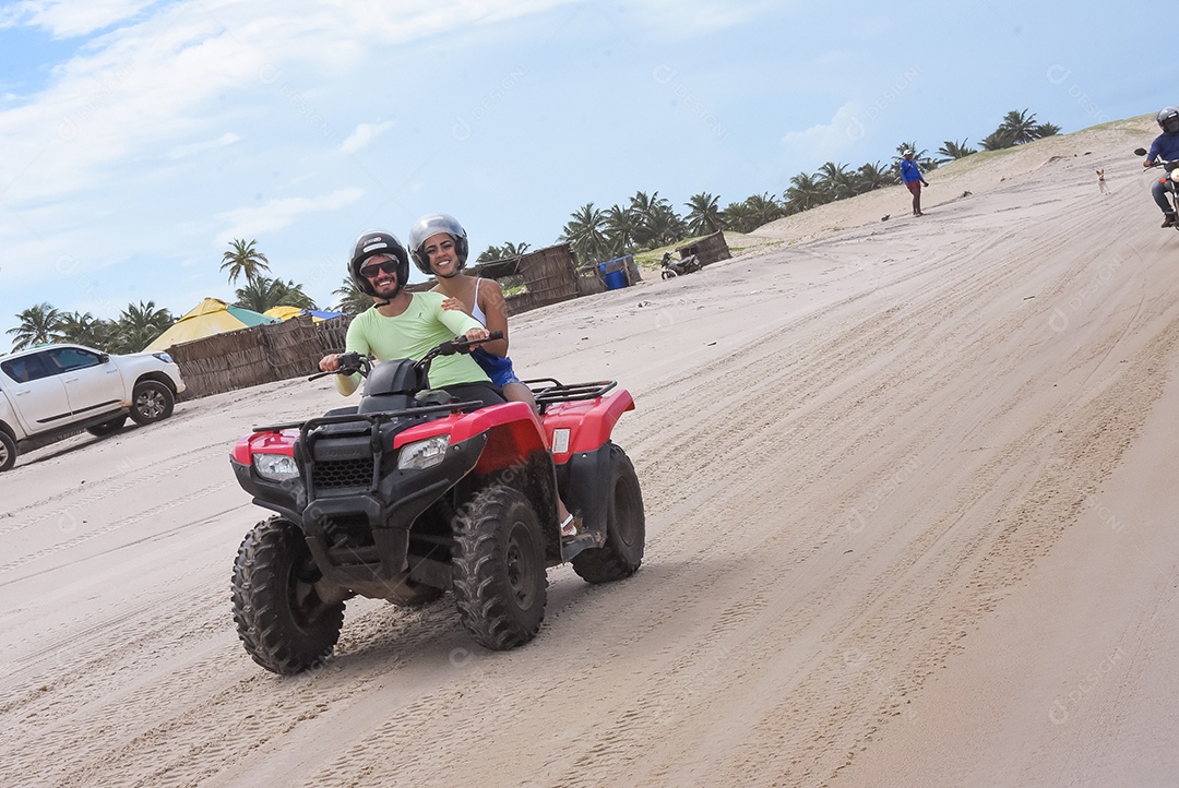 Casal curtindo férias andando de quadriciclo sobre dunas