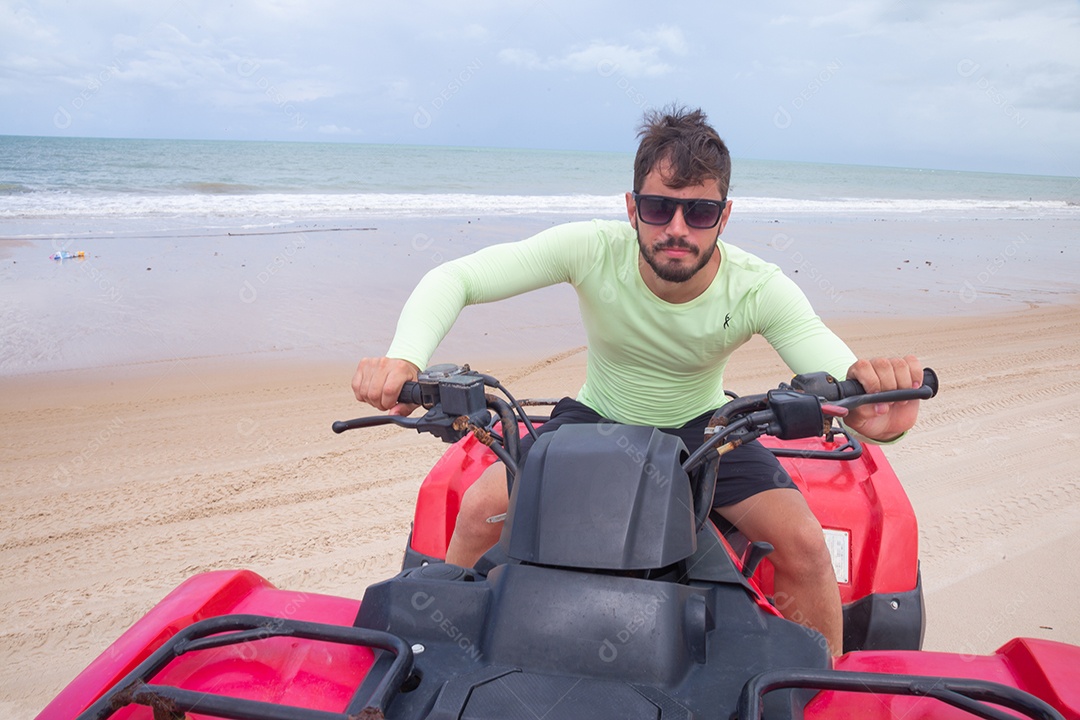 Homem jovem curtindo férias andando de quadriciclo sobre dunas