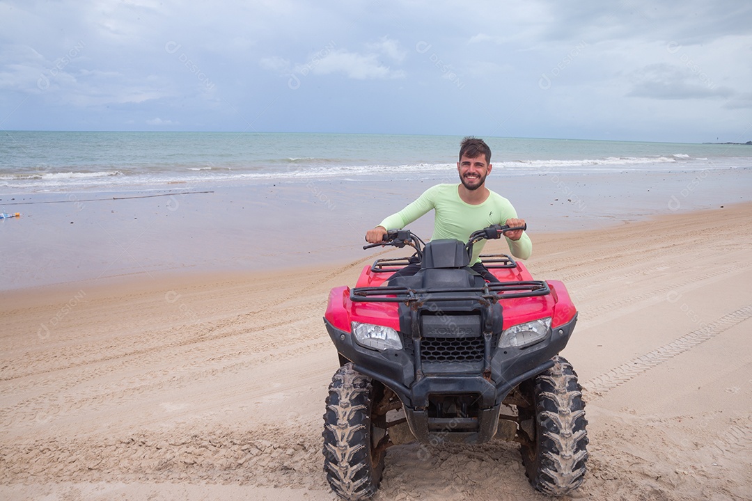 Homem jovem curtindo férias andando de quadriciclo sobre dunas