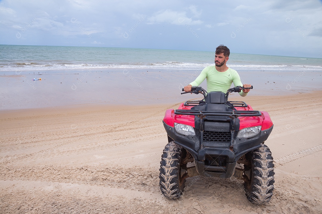 Homem jovem curtindo férias andando de quadriciclo sobre dunas