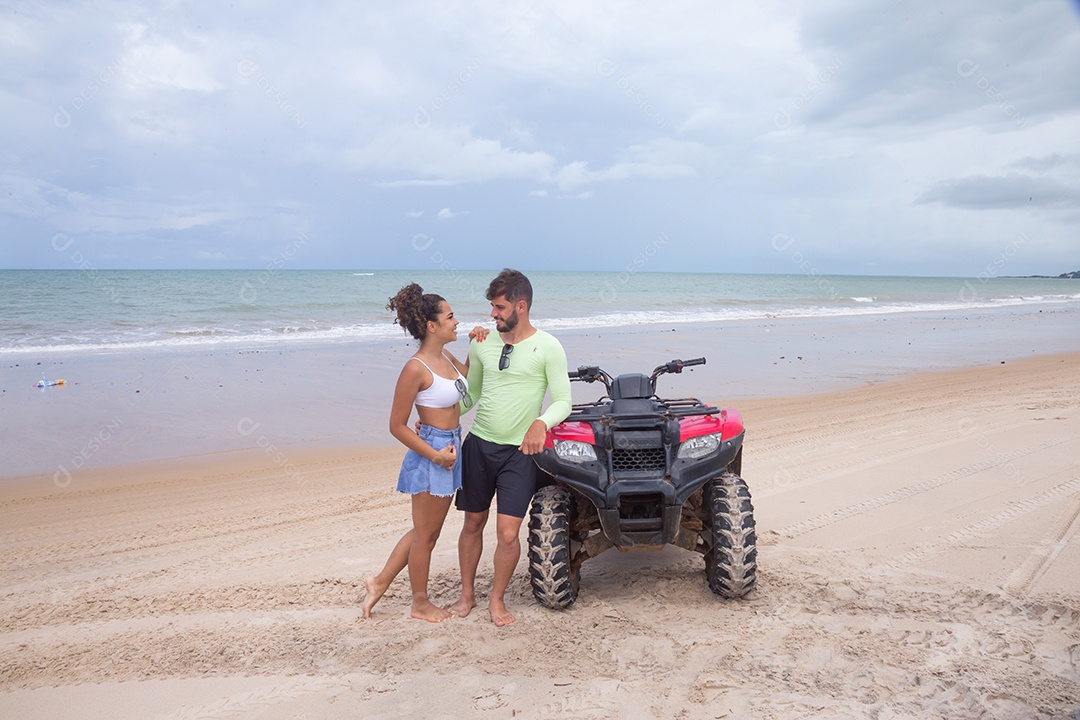 Casal curtindo férias andando de quadriciclo sobre dunas