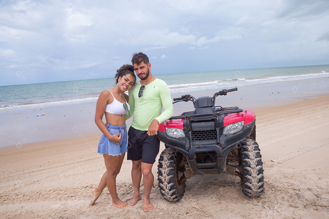 Casal curtindo férias andando de quadriciclo sobre dunas