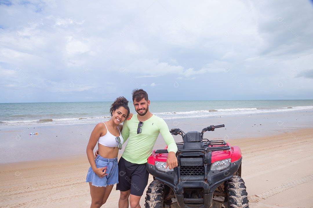 Casal curtindo férias andando de quadriciclo sobre dunas